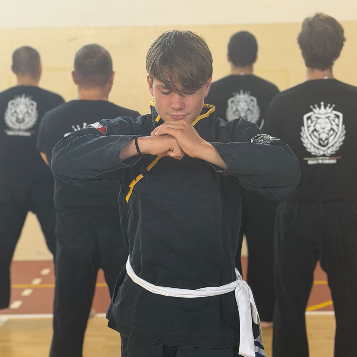 Atleta in uniforme nera che esegue il saluto tradizionale del Kung Fu
